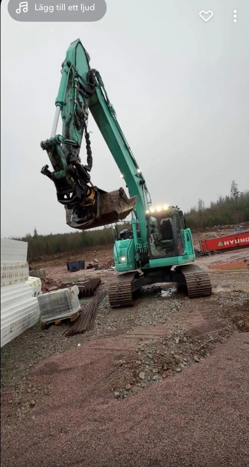 Grävmaskin på en arbetsplats intill en byggnad